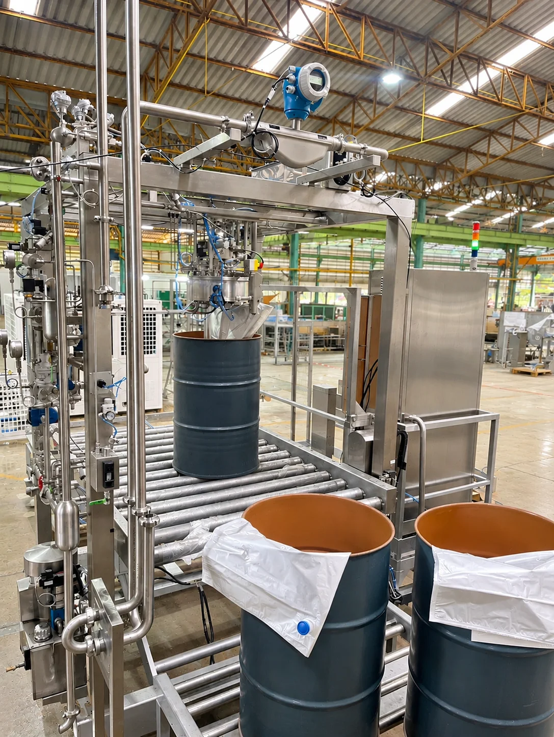 Vertical filling arrangement with a roller conveyor, drums and inner bag liners.