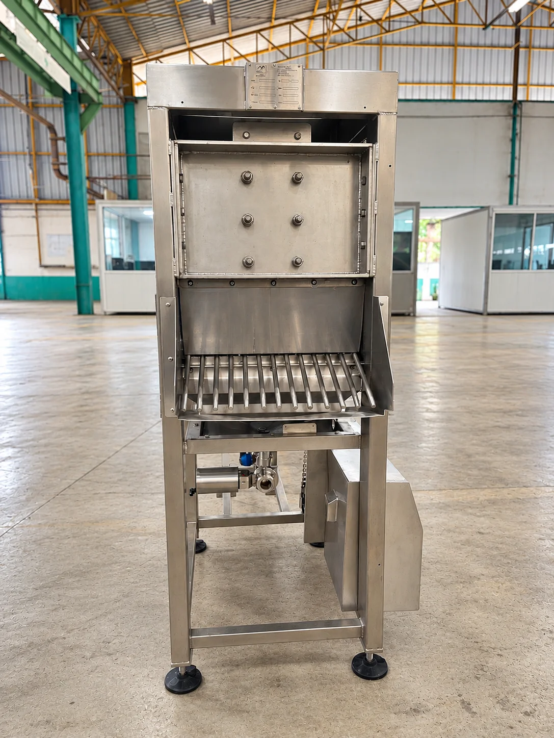 Upright stainless-steel machine with a front opening, rollers and supporting legs.