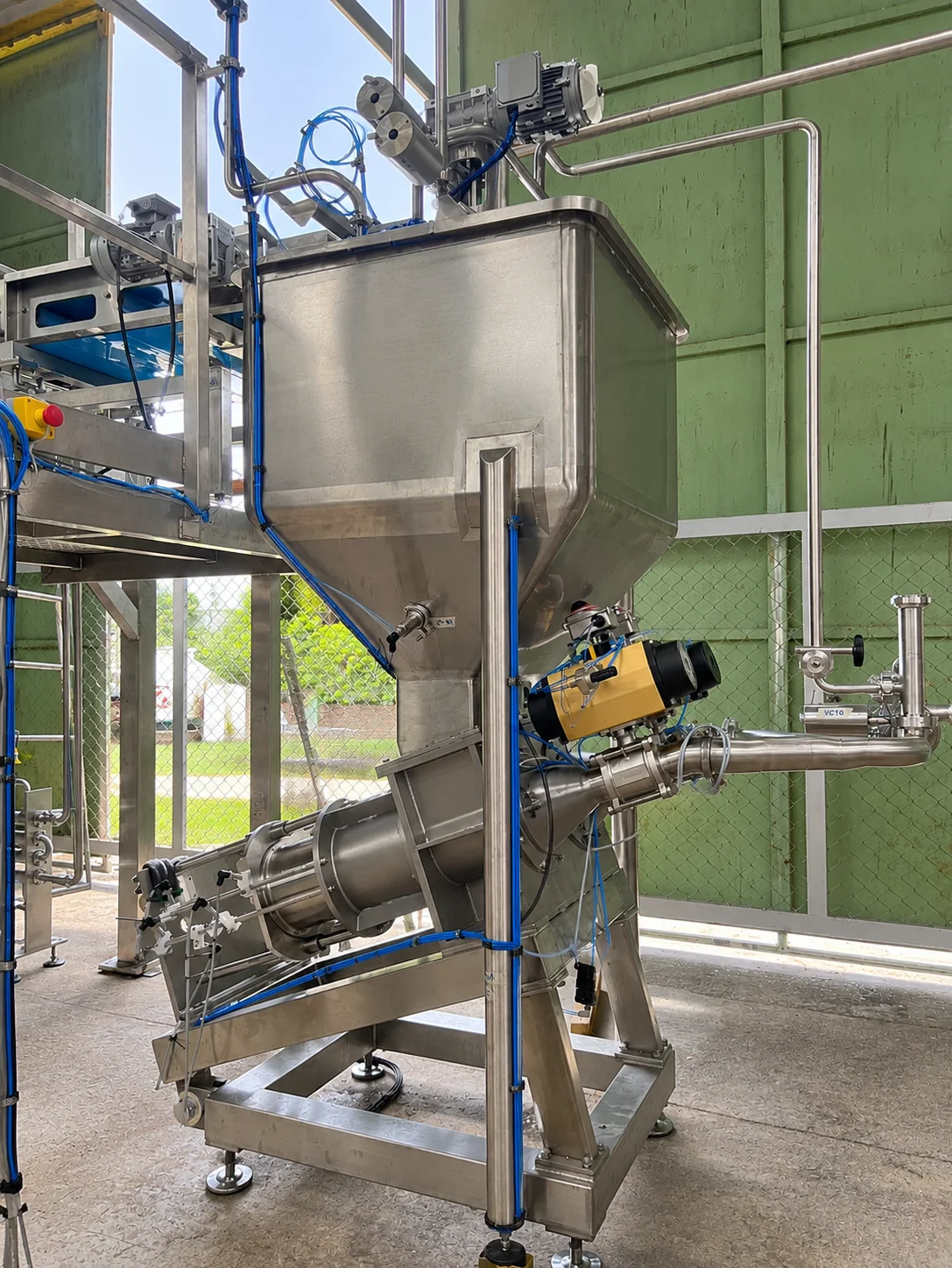 Hopper-fed piston pump on a mobile support frame.