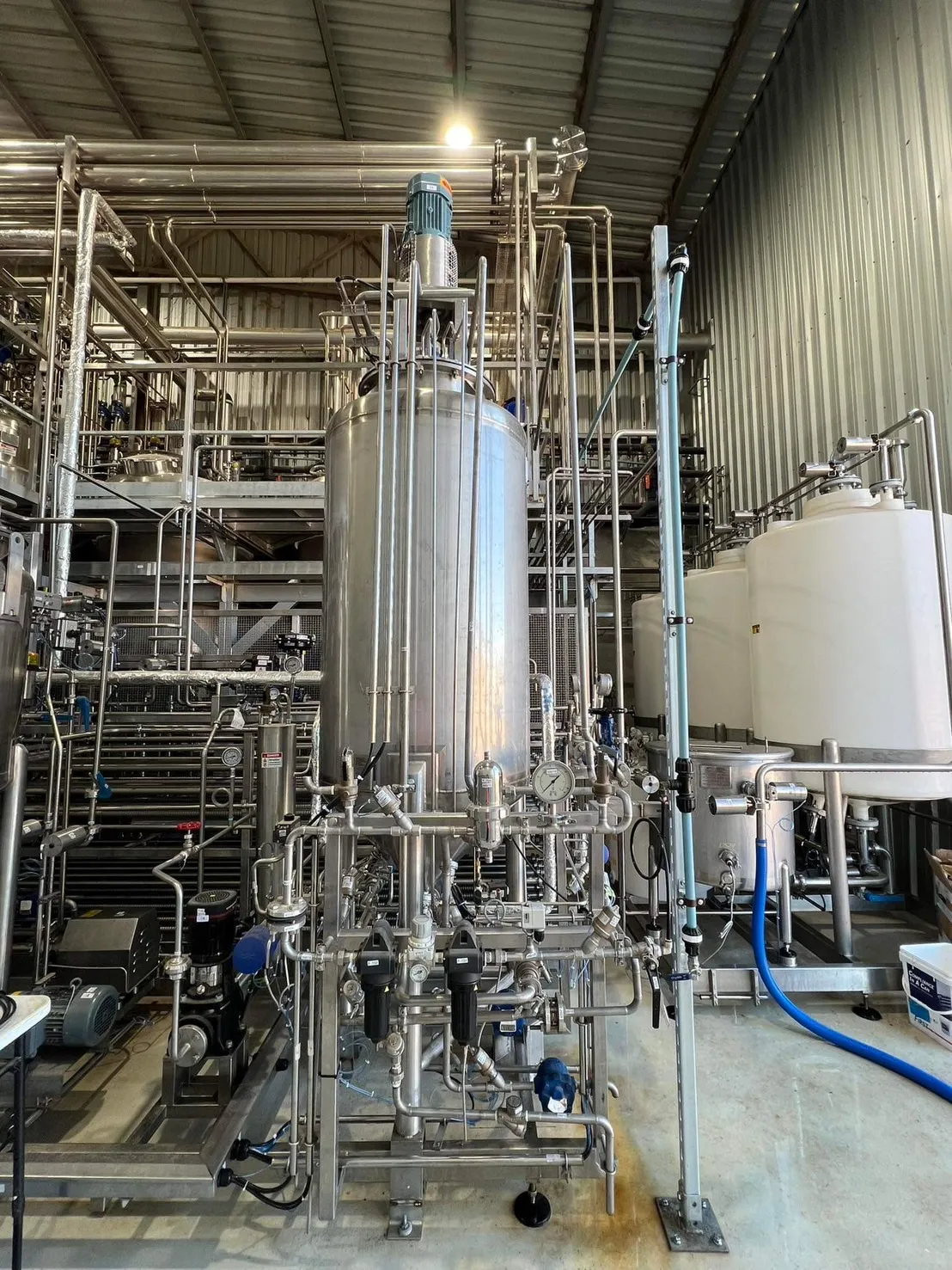 Vertical vessel with surrounding pipework and access structure.