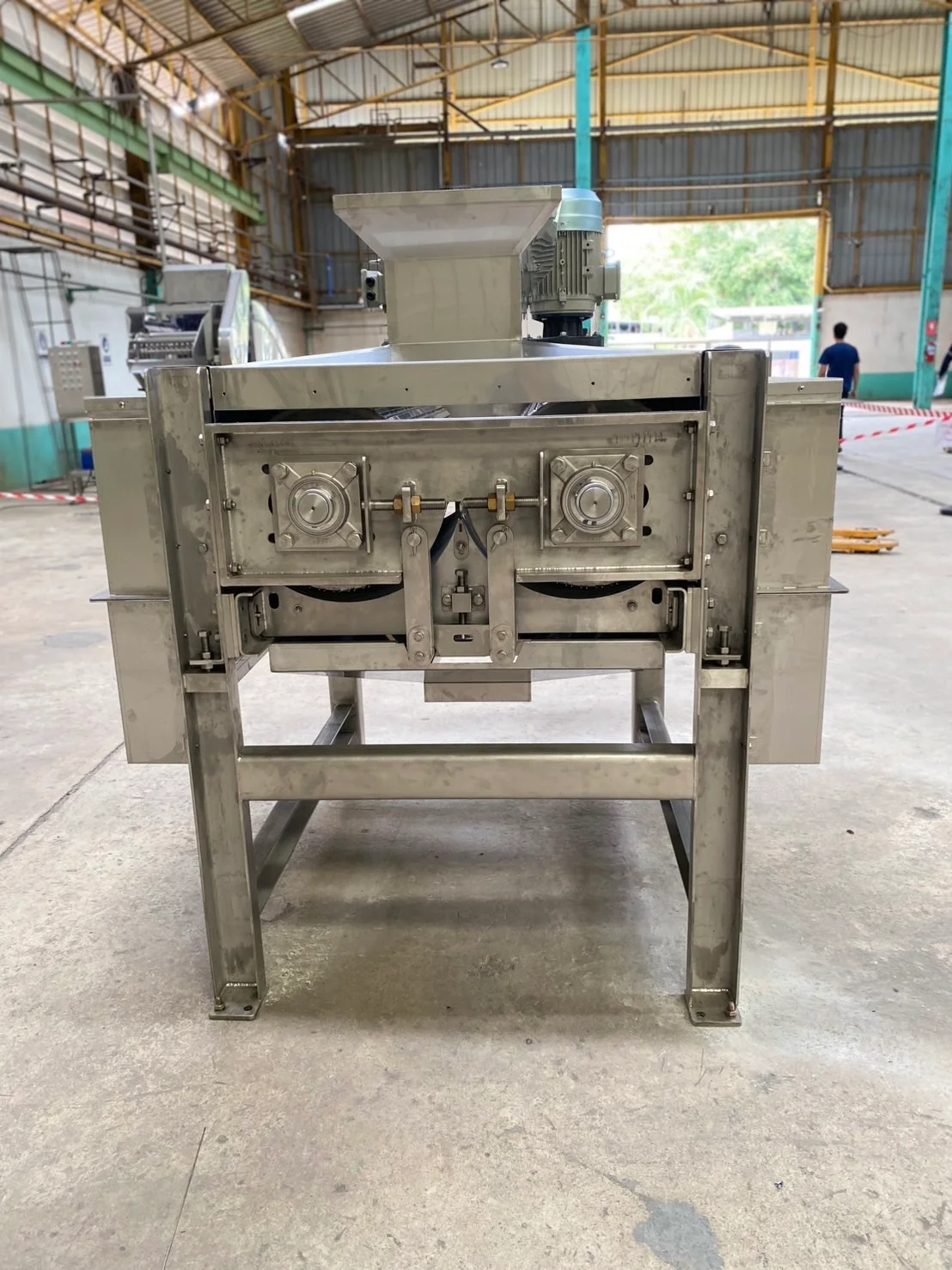 Stainless-steel machine with front access openings and support legs.