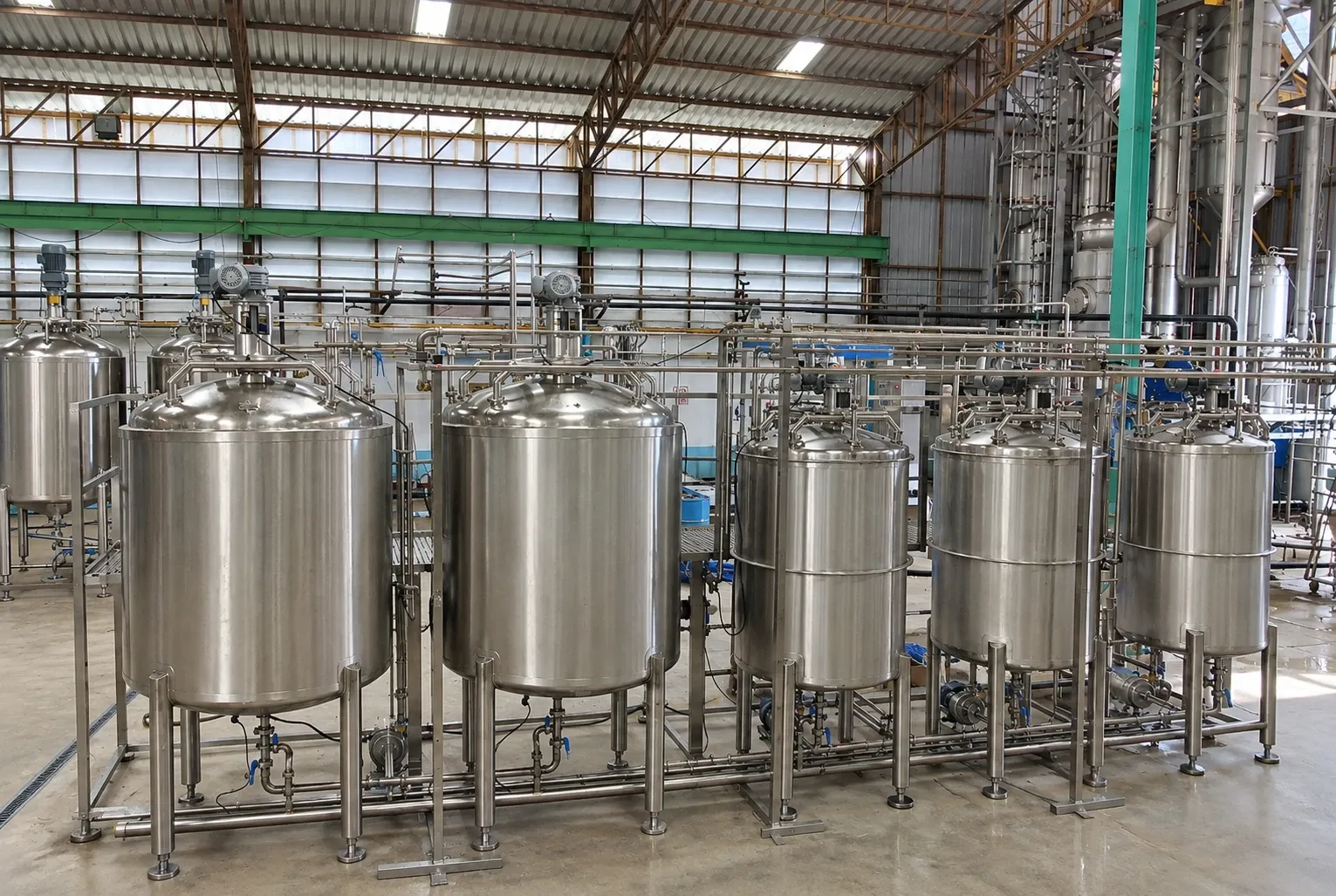 A row of stainless-steel process tanks with connected overhead pipework.