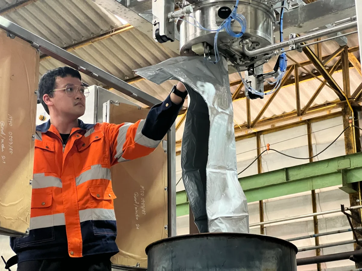 Technician handling a flexible bag beneath a filling assembly.