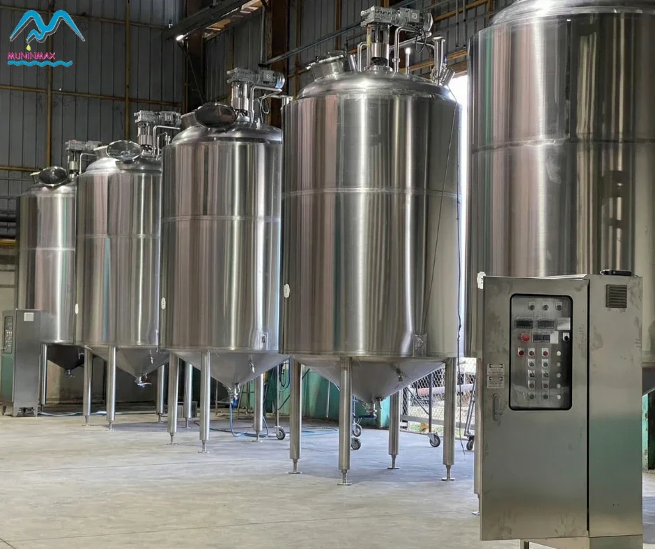 Row of stainless-steel tanks with top-mounted drives and control cabinets.